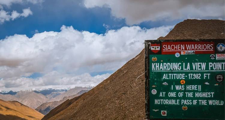 Höhenschild für Khardung La mit kargen Bergen und bewölktem Himmel