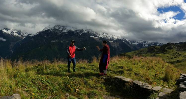 Zwei Wanderer, die auf einem grasbewachsenen Kamm herumtollen, mit dramatischen schneebedeckten Bergen im Hintergrund
