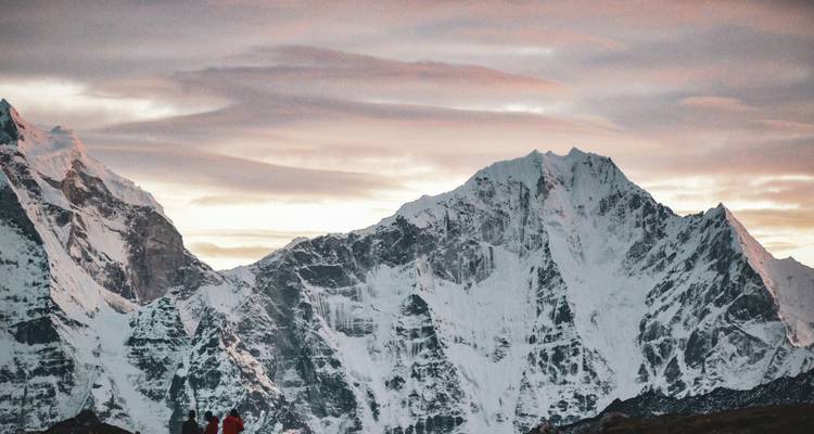Les pics enneigés de l'Himalaya brillant d'une douce lueur rose crépusculaire sous des nuages striés.