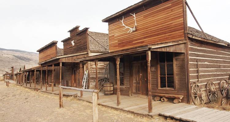 Antiguos edificios de madera de la frontera con ruedas de carreta a lo largo de una calle polvorienta