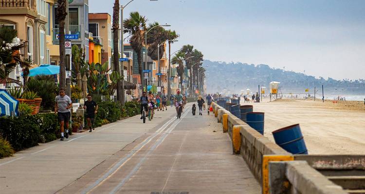 Les cyclistes, les coureurs à pied et les piétons le long d'une promenade en bord de mer à côté du sable par une journée brumeuse à San Diego.