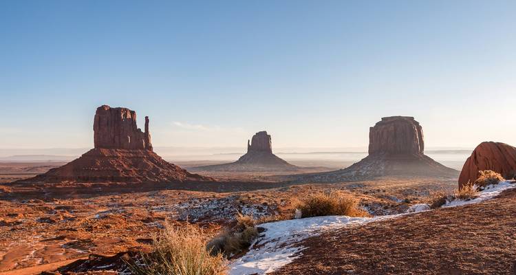 Les buttes de grès ocre de Monument Valley s'élevant depuis le désert par une matinée dégagée.