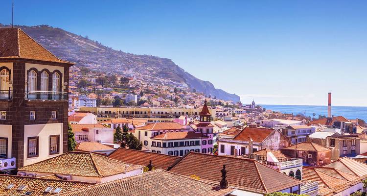 Vue surélevée sur les toits en terre cuite d'une ville côtière adossée à des collines verdoyantes et l'océan Atlantique