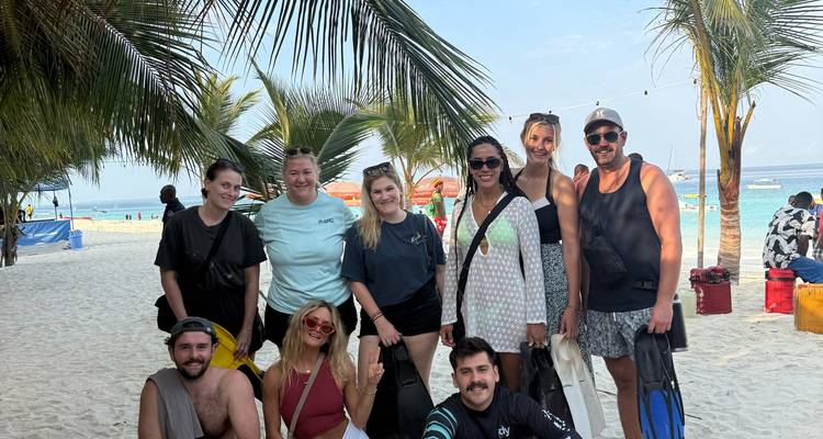 Grupo de snórquel sonriendo y posando bajo palmeras en una playa de arena blanca