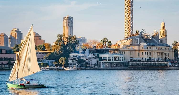 Navegación en faluca pasando por el horizonte de El Cairo con la icónica Torre de El Cairo elevándose detrás.