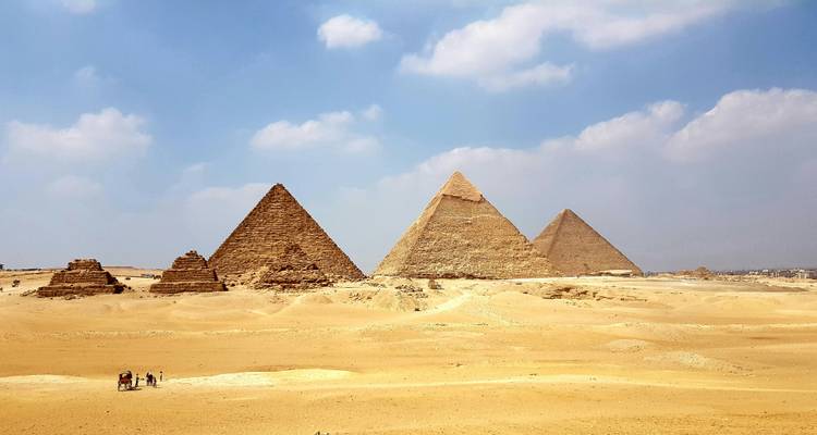 Una amplia vista del desierto que muestra toda la variedad de pirámides de Giza bajo un cielo parcialmente nublado.