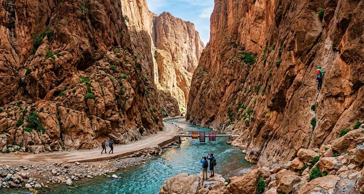 Les randonneurs et les alpinistes explorant la rivière turquoise et les murs rocheux rouge imposant de la Gorge de Todra
