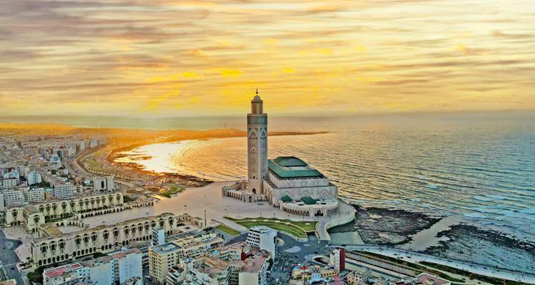 Una vista aérea espectacular de la Mezquita Hassan II sobresaliendo en el Océano Atlántico al atardecer dorado en Casablanca.