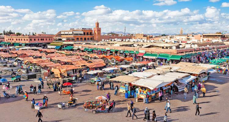 Panorama animado durante el día de la plaza Jemaa el-Fna llena de puestos, locales y visitantes en Marrakesh.