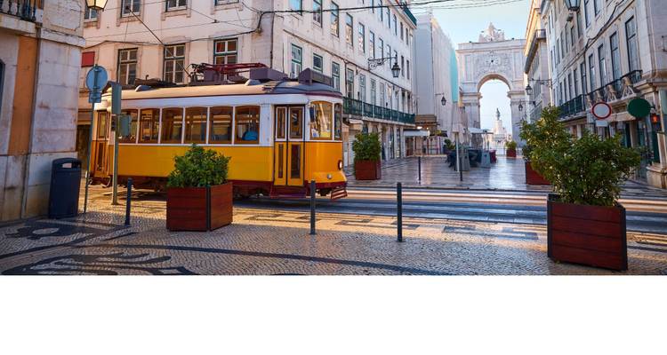 Vroege ochtendscène met gele tram bij de Rua Augusta Boog op een gedeeltelijk lege Lissabonse laan.