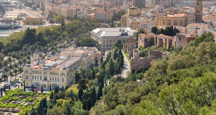 Vista elevada de la Alcazaba de Málaga, sus exuberantes jardines y los edificios de la ciudad que se mezclan con la expansión urbana.