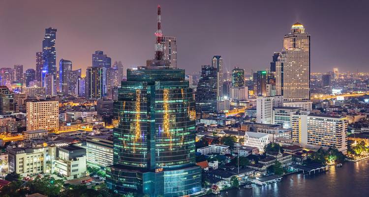 Dramatische nächtliche Skyline von Bangkok mit illuminierten Wolkenkratzern, die sich im Chao-Phraya-Fluss spiegeln.