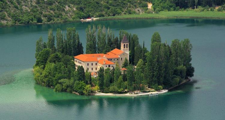 Tiny Visovac Monastery sits on a lush green islet in the tranquil lake of Krka National Park.