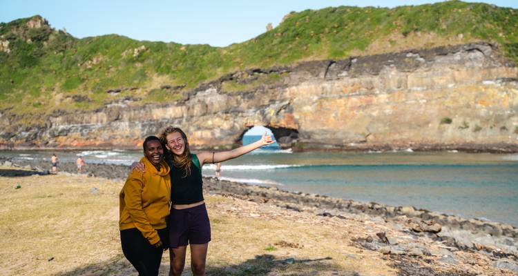 Two friends pose happily in front of the famous Hole in the Wall sea arch.