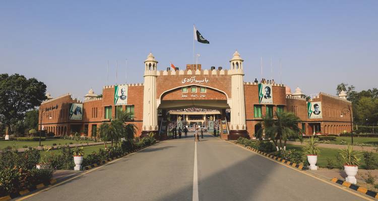 Complexe de la frontière de Wagah avec drapeau pakistanais et façade en briques rouges par une journée ensoleillée.