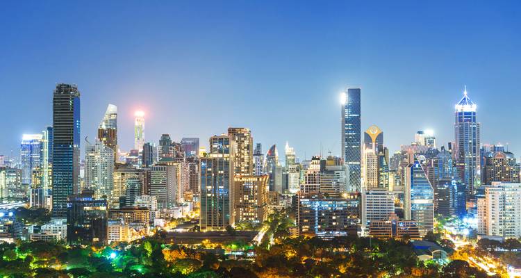 Glitzernde Skyline von Bangkok bei Nacht mit beleuchteten Wolkenkratzern und Park darunter