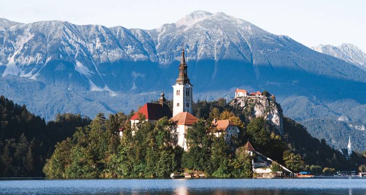 Ikonische Kirche Mariae Himmelfahrt auf der Bleder Insel vor imposanten Alpengipfeln