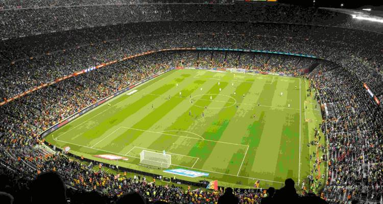 Vista aérea nocturna de un estadio de fútbol brillantemente iluminado y repleto de espectadores durante un partido.