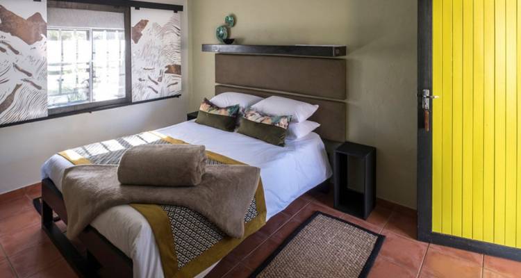 Dormitorio acogedor con cama doble, decoración en tonos tierra y toallas dobladas esperando a los huéspedes.