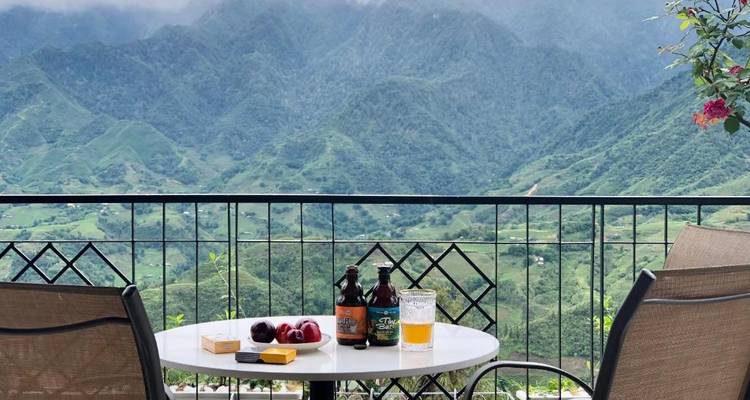Tisch im Außenbereich eines Cafés mit Craft-Bieren mit Blick auf neblige Terrassenberge in Sapa.