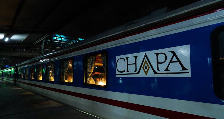 Blau-weißer CHAPA-Nachtzugwagen, nachts auf dem Bahnsteig beleuchtet.