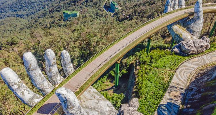 Die ikonische Goldene Brücke, gestützt durch gigantische Steinhand, die sich über die üppigen Hügel von Ba Na erstreckt.