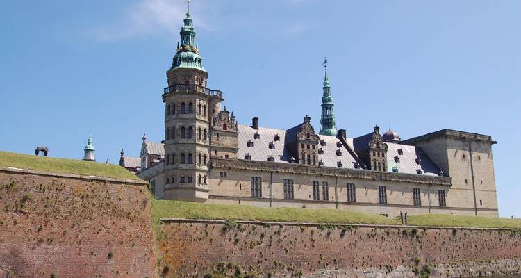El Castillo de Kronborg del Renacimiento se alza sobre gruesos bastiones de ladrillo bajo un cielo azul despejado.