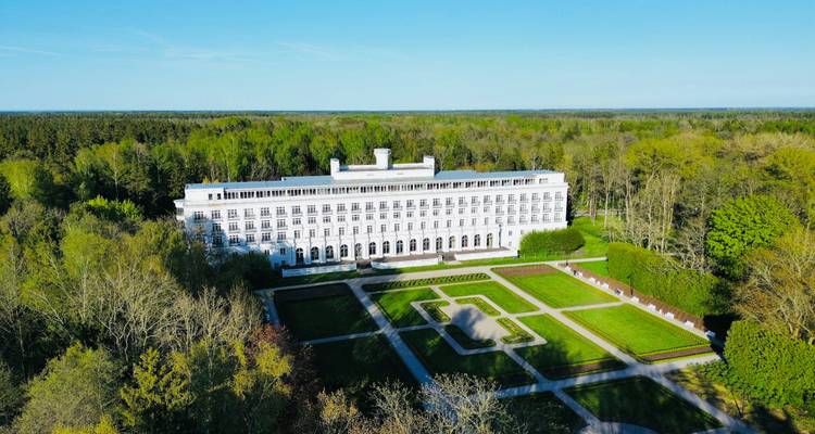 Langes weißes Spa-Resort-Gebäude inmitten eines riesigen grünen Waldes und gepflegter Gärten