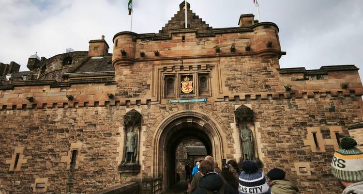 Los turistas se reúnen en la entrada arqueada del Castillo de Edimburgo, construido con arenisca de tonos cálidos.