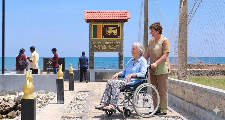 Un viajero mayor en silla de ruedas disfruta de un paseo por la costa con asistencia, un cartel con la bandera de Sri Lanka y el océano azul de fondo.