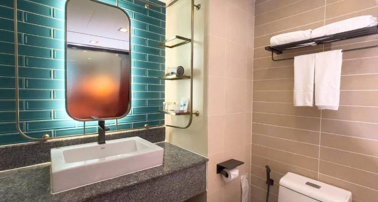 Modernes Hotelbadezimmer mit blaugrünen U-Bahn-Fliesen, rechteckigem Waschbecken und großem Spiegel.