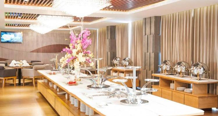 Buffetrestaurant des Hotels mit Kronleuchtern, rosafarbenen Blumendekoration in der Mitte der Tische und Servierstation.