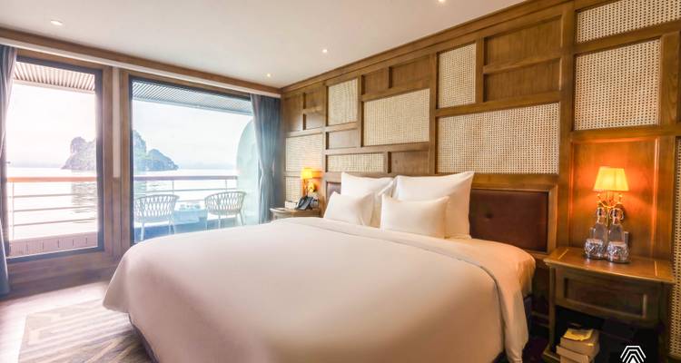 Camarote de crucero de lujo con cama king size y vista al balcón de las islas de karst sobre el agua.