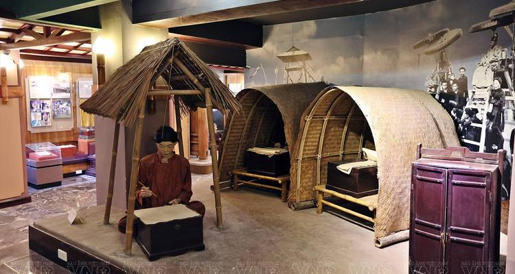 Exhibición de museo en interiores con refugios con techo de paja y un maniquí de tamaño natural de un escriba.