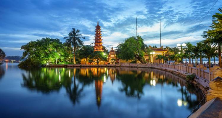 La Pagoda Tran Quoc iluminada al atardecer reflejándose en un tranquilo lago.