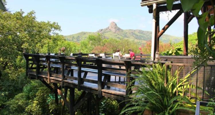 Plataforma de observación elevada de madera con vistas a un exuberante valle verde y un distintivo pico montañoso rocoso