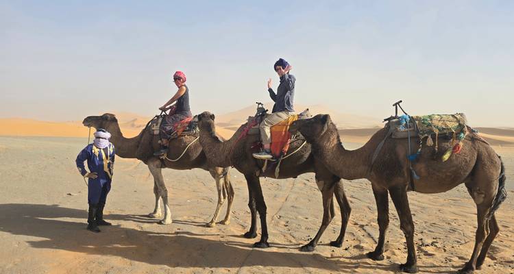 El guía lleva a dos turistas montados en camellos a través de la enorme extensión de arena del Sahara.