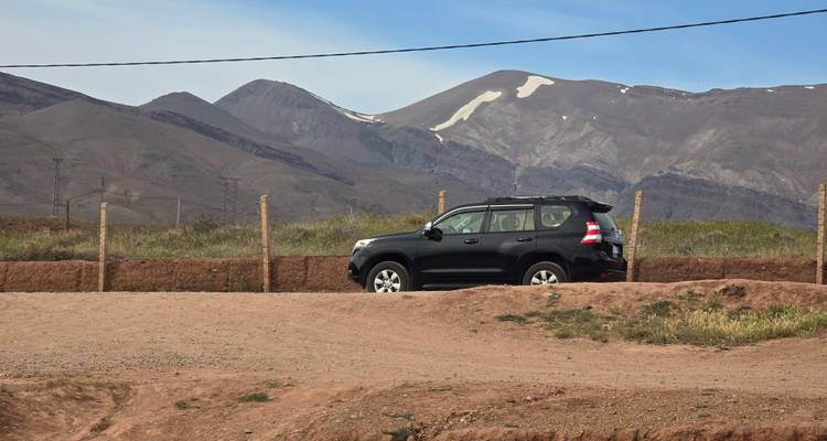 SUV estacionado en un camino de tierra con las montañas del Atlas nevadas de fondo
