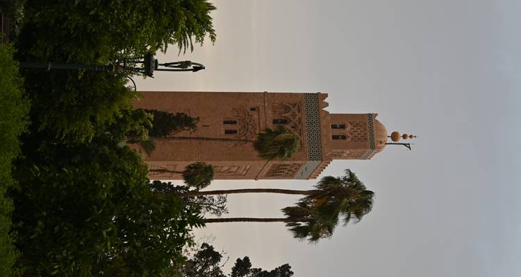 El minarete de arenisca de la Mezquita Koutoubia se alza sobre las palmeras bajo un suave cielo matutino en Marrakech.