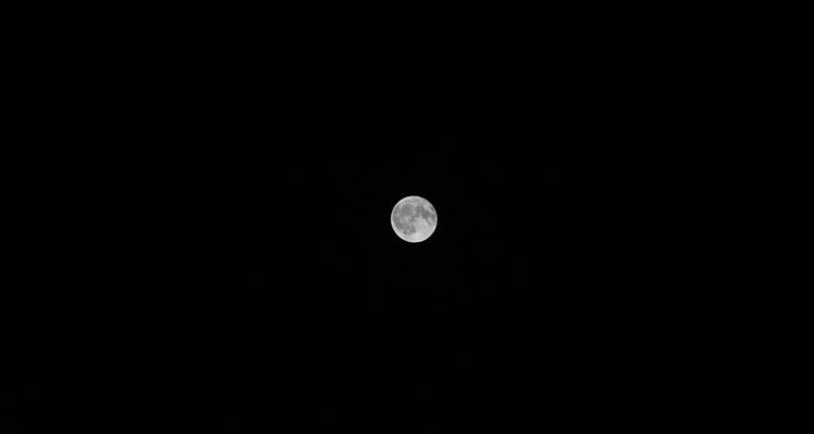 Luna llena aislada capturada con nitidez contra un cielo nocturno negro.