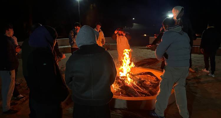 Reunión nocturna alrededor de una fogata en el desierto del Sahara bajo iluminación mínima