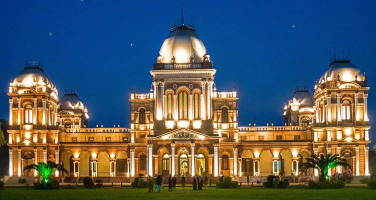 Grootschalig verlichte Noor Mahal-paleis dat tegen de nachtelijke hemel oplicht.