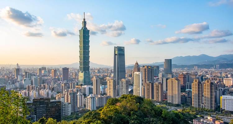 Skyline von Taipei mit dem Taipei 101, das sich über die dichte Stadtlandschaft unter blauem Himmel erhebt.