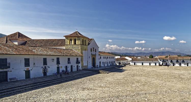 Vaste place principale pavée de pavés de la Villa de Leyva bordée de bâtiments coloniaux blancs et de montagnes.