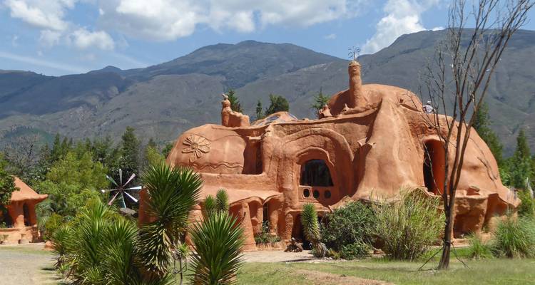 Structure capricieuse en terre cuite Casa Terracota se dressant contre des jardins verdoyants et des montagnes.