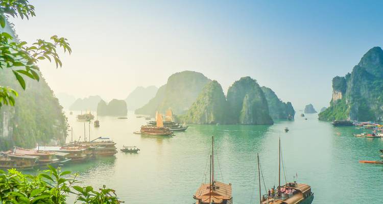 Dreamy panorama of emerald waters and limestone karst islands dotted with traditional boats in Halong Bay.