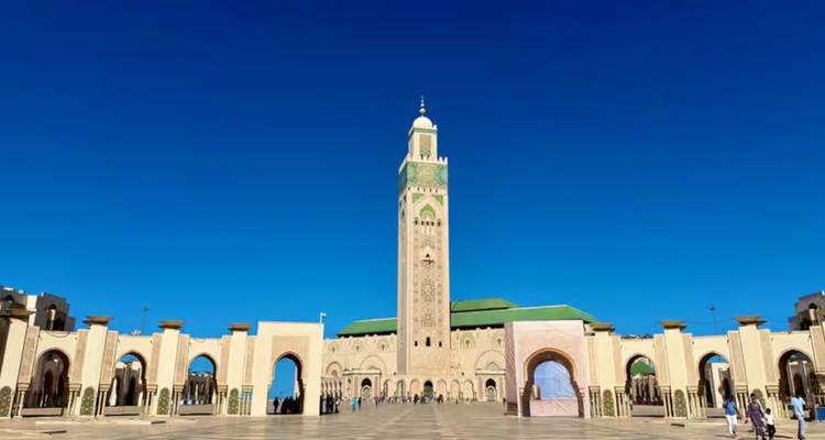 Front view of the Hassan II Mosque and its towering minaret against a deep blue sky in Casablanca.