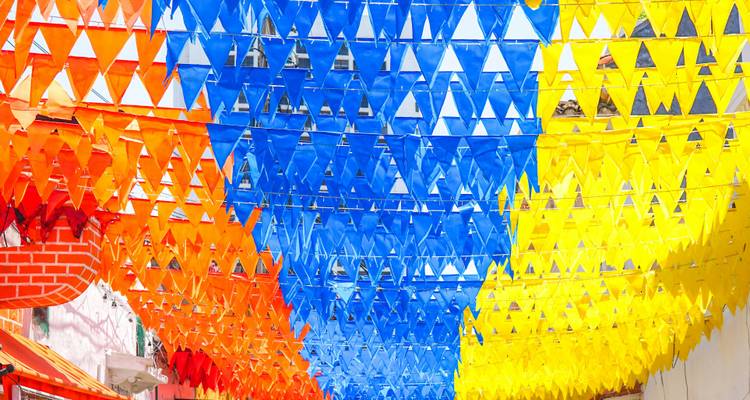 Ceiling of colorful triangular flags in bright orange, blue and yellow forming a festive canopy.
