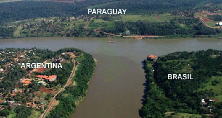 Imagen aérea de la Triple Frontera con texto superpuesto etiquetando Paraguay, Argentina y Brasil.