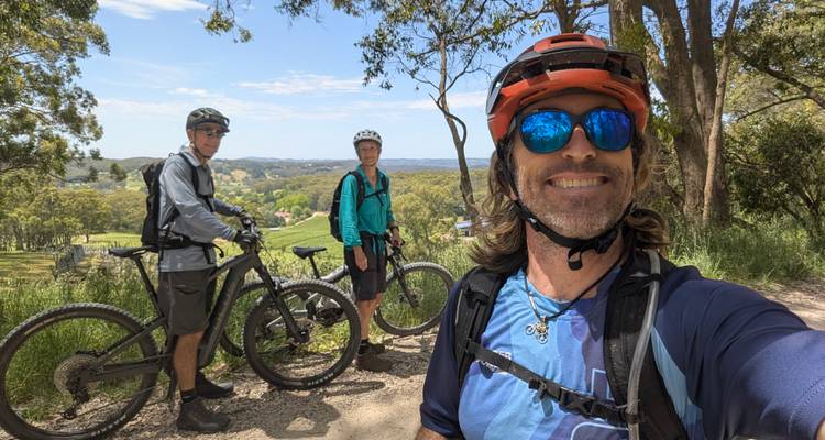 Radfahrer machen eine Pause auf einem Feldweg mit panoramischen Blicken auf die ländliche Umgebung, während ein Fahrer ein Selfie macht.